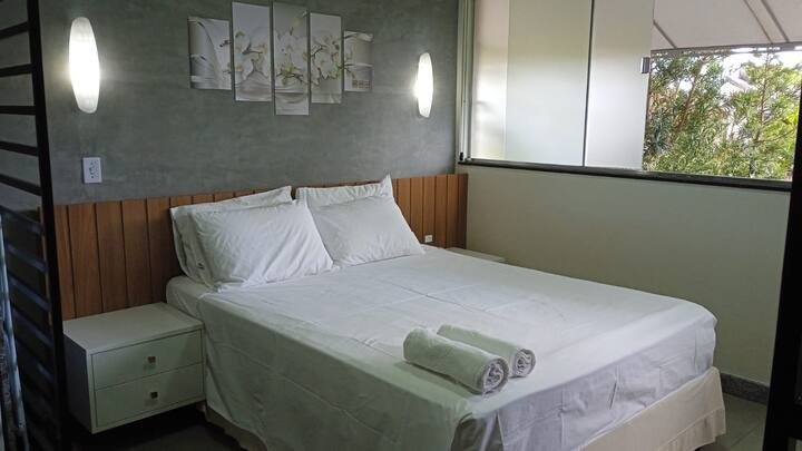 Quarto principal com cama king size e cabeceira de madeira