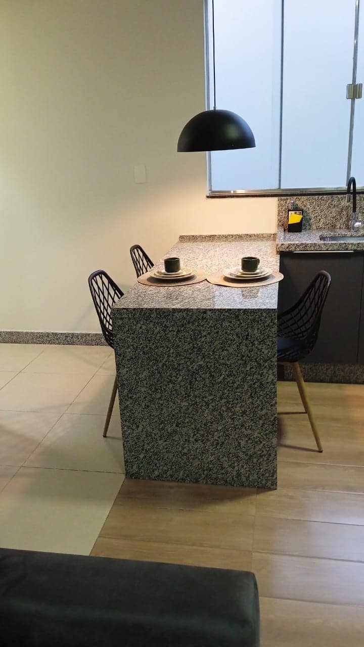 Bancada da cozinha com luminária pendente e cadeiras modernas