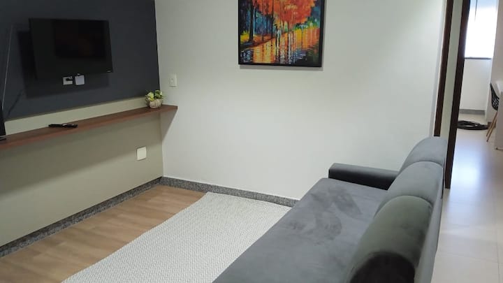 Sala de estar com sofá cinza e quadro colorido